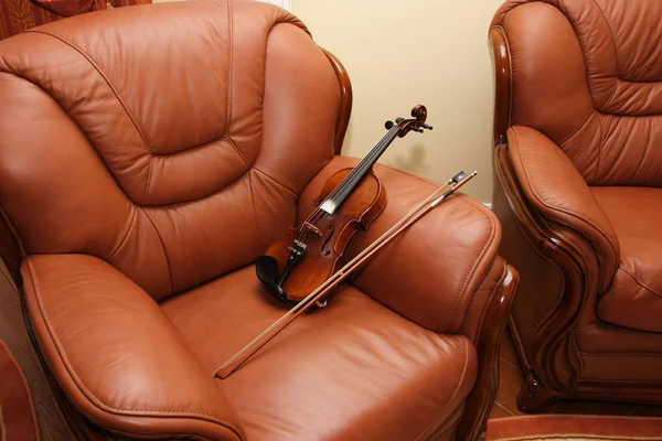 Скрипка на кожаном стуле — стоковое фото