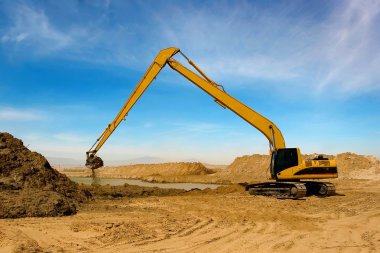 Orange excavator at Construction irrigation canal in Desert clipart