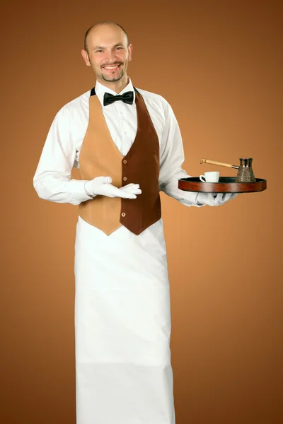Официант в форме с кофеваркой и чашкой кофе . — стоковое фото