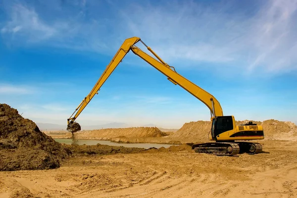 Orange grävmaskin på konstruktion bevattning canal i öknen — Stockfoto
