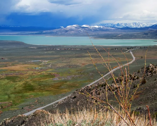 stock image Landscape with long road, lake and mountains