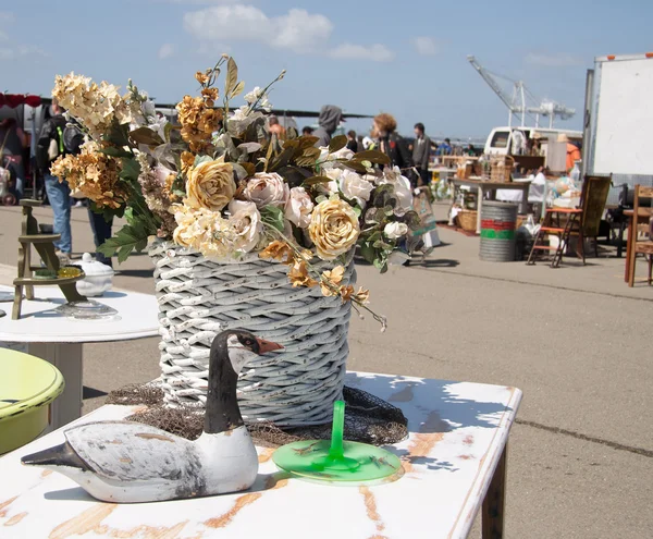 Bloemen en houten eend op rommelmarkt — Stockfoto