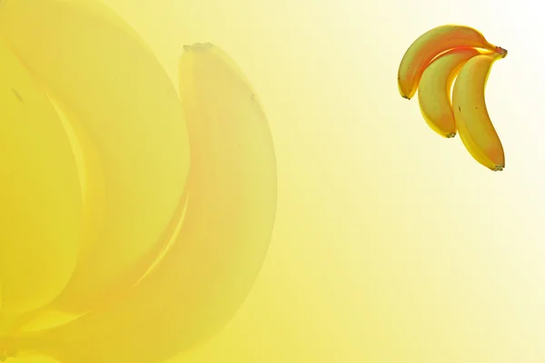 Tres plátanos maduros sobre fondo abstracto amarillo — Foto de Stock