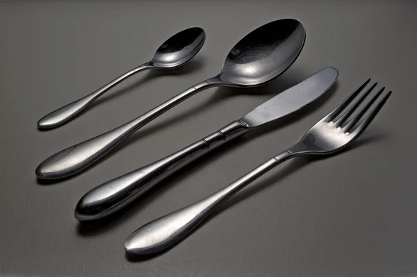 stock image Shiny cutlery set on black leather background