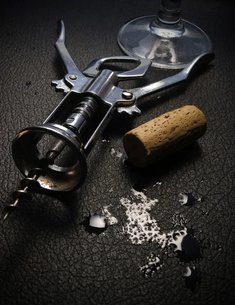 stock image Corkscrew with wine cork and glass on black wet surface