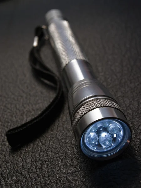 Steel flashlight on black surface — Stock Photo, Image