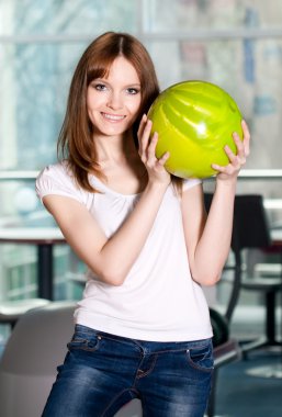 Yeşil bowling topuyla gülümseyen genç kız.