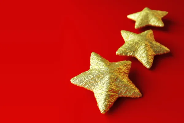Tre gyllene stjärnor på röd bakgrund — Stockfoto