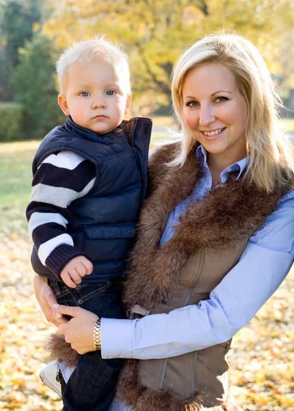 Lindo niño y bonita mamá al aire libre en otoño . — Foto de Stock