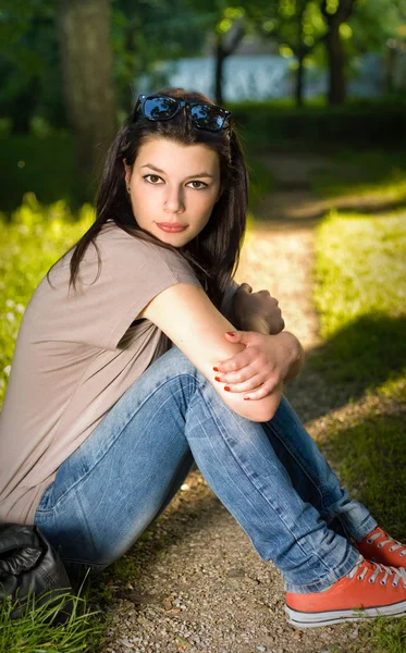 Porträt der schönen jungen Brünette sitzt entspannt im Park — Stockfoto