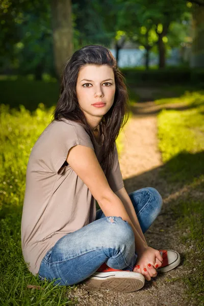 Portret młoda brunetka siedzący spokojny w parku — Zdjęcie stockowe
