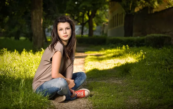Retrato de bela jovem morena sentada relaxada no parque — Fotografia de Stock
