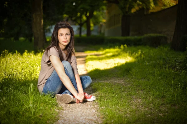 公園でリラックスして座っている美しい若いブルネットの肖像画 — ストック写真