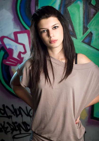 Urban portait of a beautiful young brunette girl with graffiti b — Stock Photo, Image