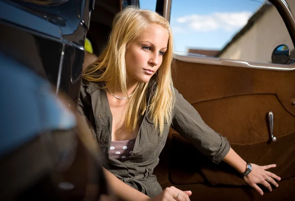 Belle jeune fille blonde dans une voiture vintage noire . — Photo