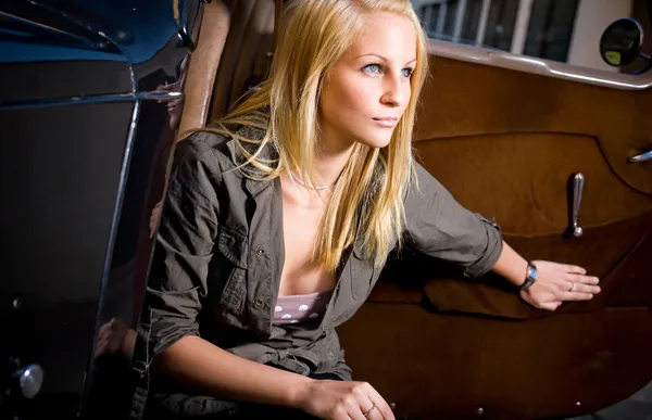 Schöne junge blonde Mädchen in einem schwarzen Oldtimer. — Stockfoto