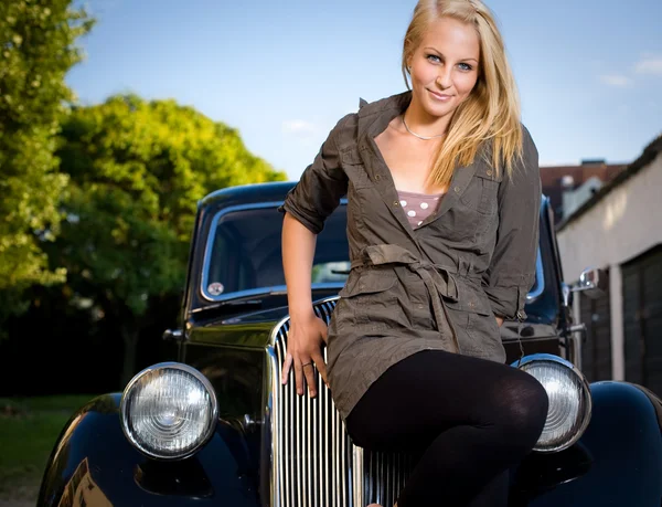 Piękna blond dziewczyna z czarnym rocznika samochodu. — Zdjęcie stockowe