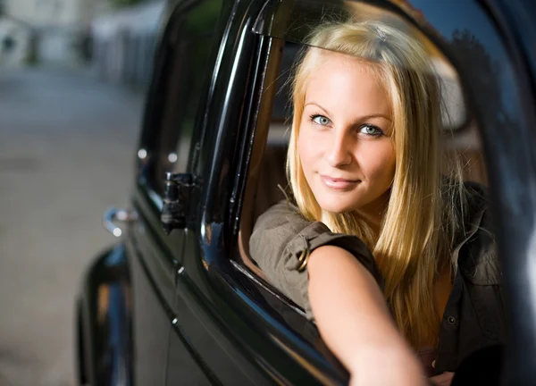 Bella ragazza bionda in una macchina d'epoca nera . — Foto Stock