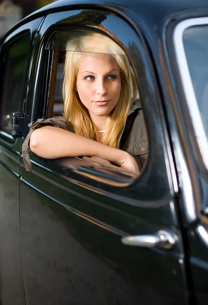 Bella ragazza bionda in una macchina d'epoca nera . — Foto Stock