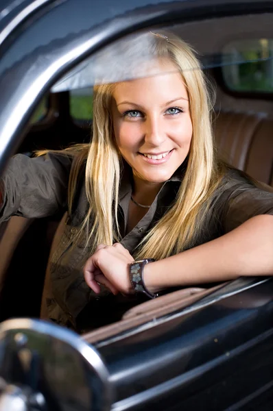 Beautiful young blond girl in a vintage car. — Stock Photo, Image