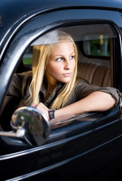 Hermosa joven rubia en un coche vintage negro . —  Fotos de Stock