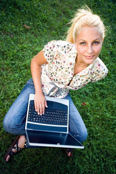 Beautiful young blond using laptop outdoors in nature. — Stock Photo, Image