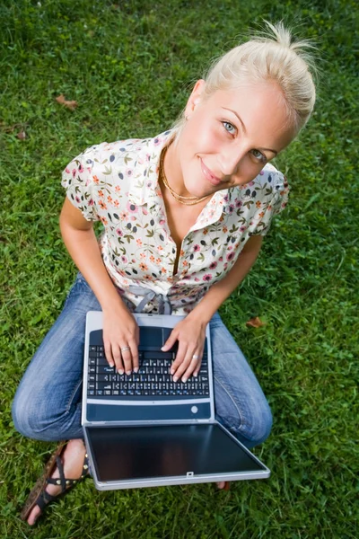 Mladá blondýna pomocí notebooku venku v přírodě. — Stock fotografie