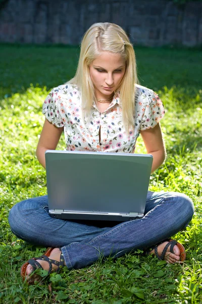 Hermosa rubia joven que se divierte con el ordenador portátil al aire libre — Foto de Stock