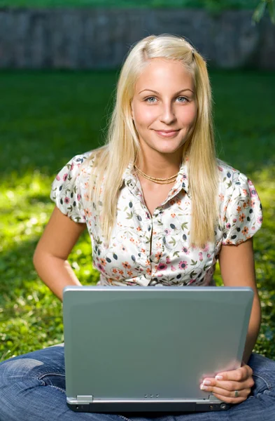 Красивая молодая блондинка развлекается с ноутбуком на открытом воздухе — стоковое фото
