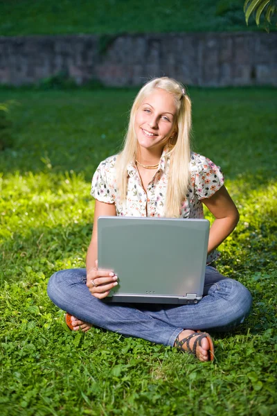 Linda jovem loira se divertindo com laptop ao ar livre — Fotografia de Stock