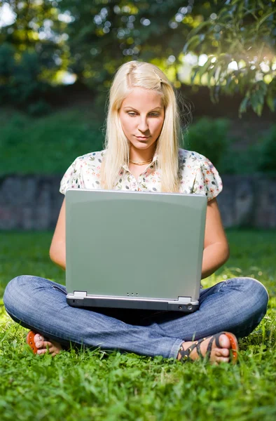 Beautiful young blond using laptop outdoors in nature. — Stock Photo, Image