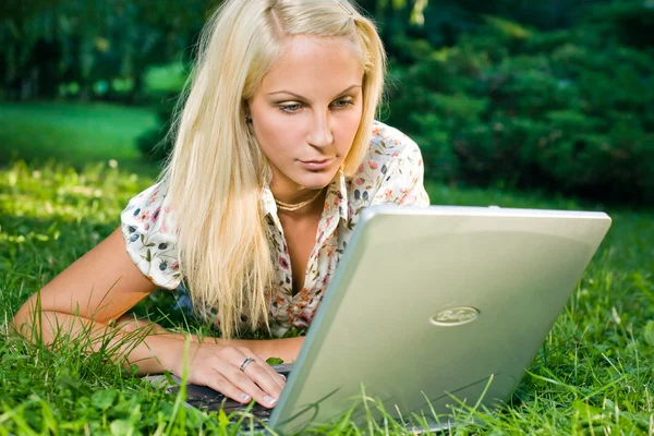 Bella giovane bionda utilizzando il computer portatile all'aperto in natura . — Foto Stock