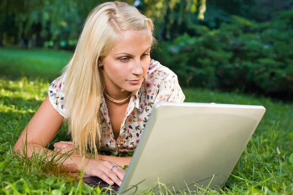 Belle jeune blonde utilisant un ordinateur portable en plein air dans la nature . — Photo