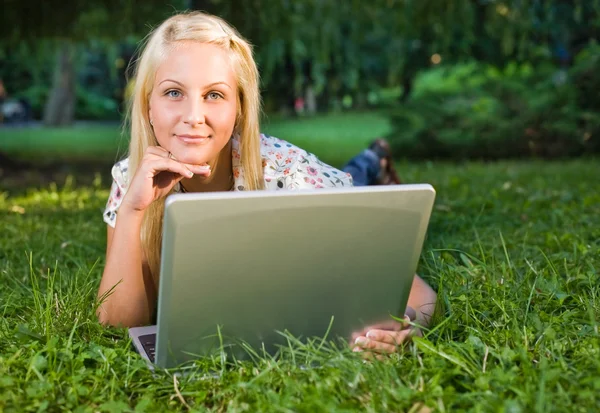 Hermosa rubia joven usando el ordenador portátil al aire libre en la naturaleza . —  Fotos de Stock