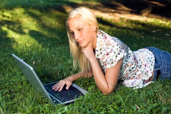 Όμορφη νεαρή ξανθιά χρησιμοποιώντας φορητό υπολογιστή σε εξωτερικούς χώρους στη φύση. — Φωτογραφία Αρχείου