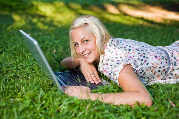 Hermosa rubia joven usando el ordenador portátil al aire libre en la naturaleza . — Foto de Stock