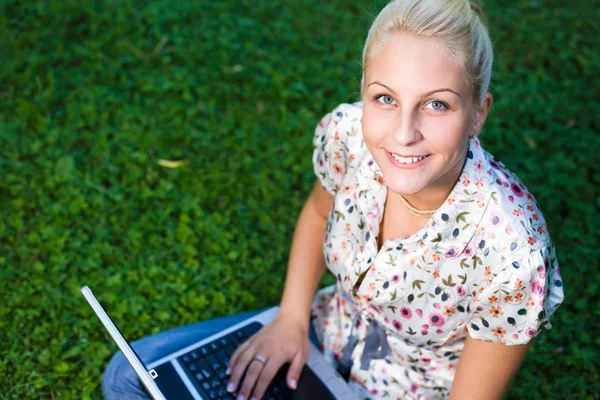 Чудова молода блондинка розважається з ноутбуком на відкритому повітрі — стокове фото