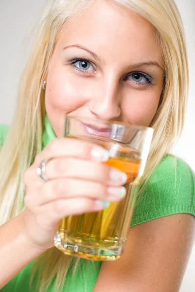 Mooie jonge blonde meisje houdt van een glas appelsap, focu — Stockfoto