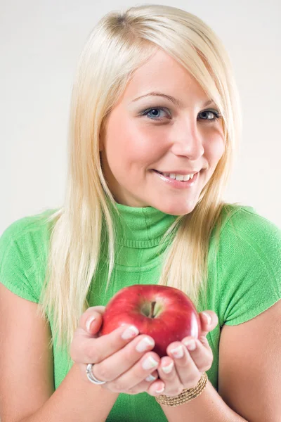 Fitte junge Blondine bietet einen roten Apfel an. — Stockfoto