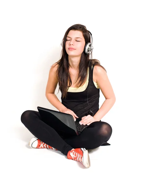 Чудова молода брюнетка слухає музику за допомогою ноутбука . — стокове фото
