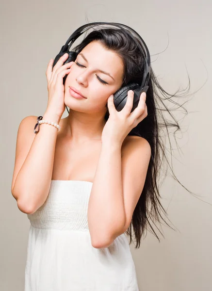 Bruneta ponořen v hudbě sluchátka. — Stock fotografie