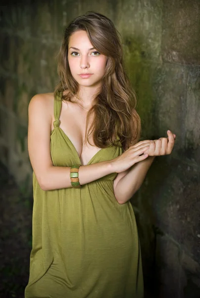 Vacker ung brunett poserar i grön klänning. — Stockfoto