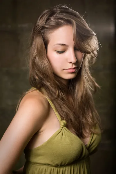 Krásná mladá brunetka pózuje v zelených šatech. — Stock fotografie