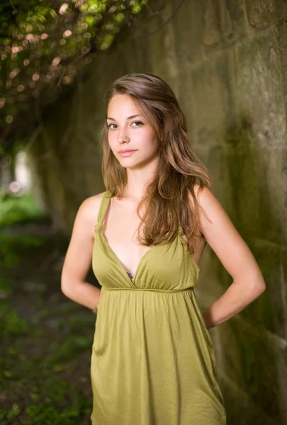Prachtige jonge brunette in groene jurk buitenshuis. — Stockfoto