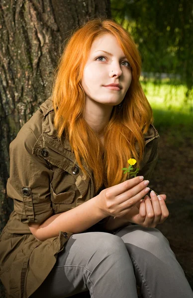 Romantisches Porträt eines jungen rothaarigen Mädchens, das im Park sitzt. — Stockfoto