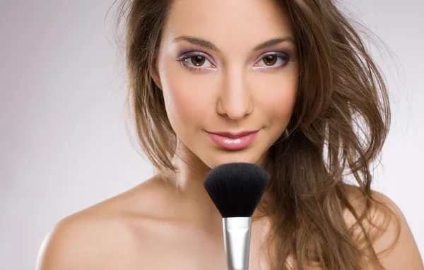 Jeune femme brune avec brosse de maquillage . — Photo