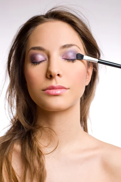 Prachtige brunette vrouw met hulpmiddelen voor make-up borstels. — Stockfoto