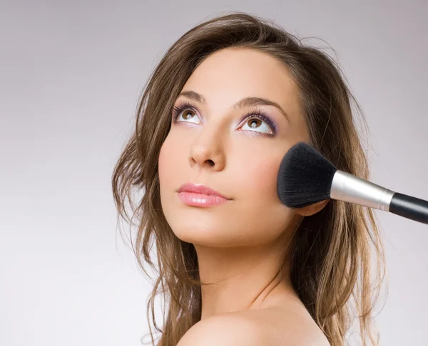 Prachtige brunette vrouw met hulpmiddelen voor make-up borstels. — Stockfoto
