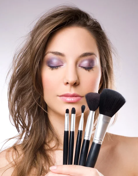 Mulher morena lindo com ferramentas de maquiagem, escovas . — Fotografia de Stock