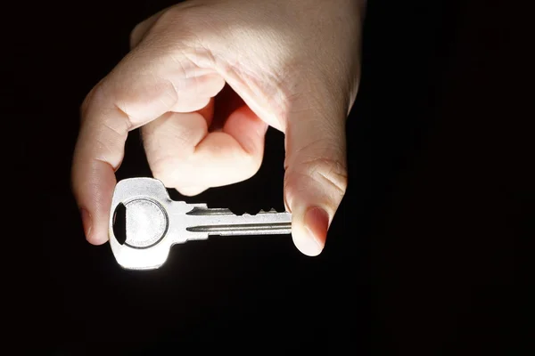 Ręka trzyma klucz między kciukiem i palcem wskazującym — Zdjęcie stockowe